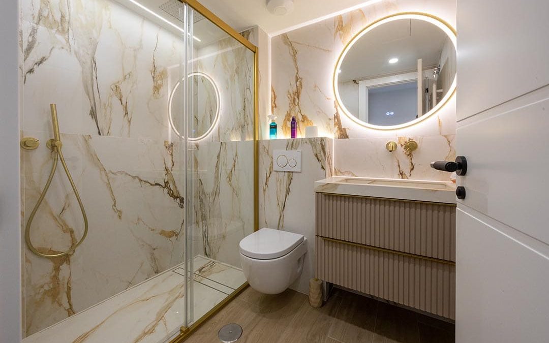 Baño de diseño con efecto mármol y detalles dorados.
